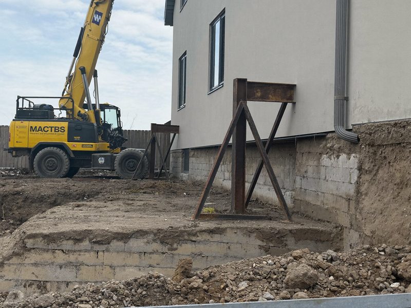 Steel piers set in an excavated trench against a house footing